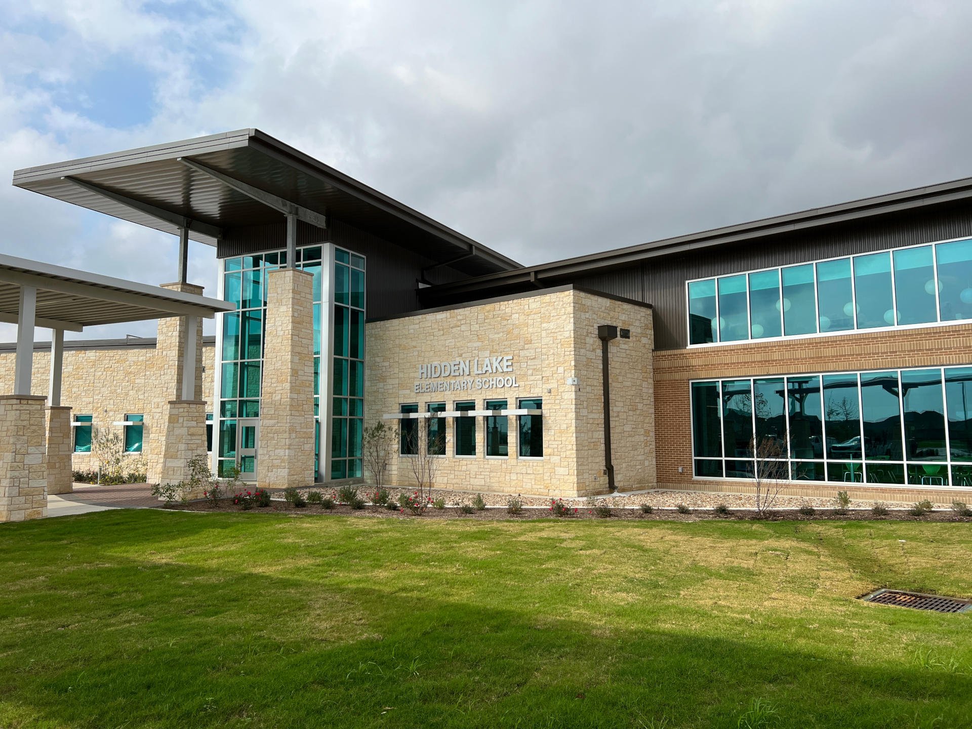 Pflugerville ISD – Elementary School #23  Pflugerville ISD’s Elementary School #23 consists of new construction of a two-story, 116,000 SF elementary building on 23.44 acres of undisturbed land.  Public work included an extension of Hidden Lake Drive and a collector road to be deeded over to the City of Pflugerville.  The building consists of classrooms for K-5 with multiple collaborative learning areas and media center.  Exterior building façade includes brick, stone, metal panel, and glass curtainwall.  Site work includes car rider drop-off, two detention ponds, multiple aluminum canopies, covered basketball court, playgrounds with poured in place surfacing, tensioned shade structures, outdoor learning spaces, and walking track.  Back to Portfolio 